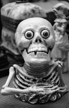 Funny greedy skeleton figurine at flea market in Paris (France). Death concept. Black and white photo.