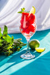 Pieces of watermelon with mint leaves and lime in a glass on a green background