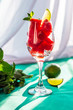 Pieces of watermelon with mint leaves and lime in a glass on a green background