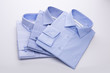 Three blue men's shirts folded in a pack on a white background.