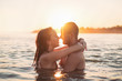 © Karanov images - Couple in water at sea, hugging, at sunset, golden hour
