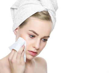 Wall Mural - attractive young blond woman with her hair wrapped in a towel, removing make up. pretty girl with pe
