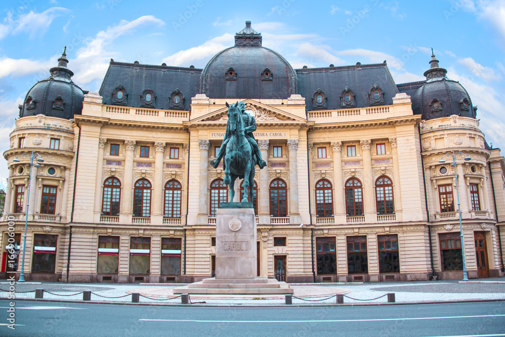 Beautiful view of the building of the Central University Library with equestrian monument to King Karol I in front of him in Bucharest, Romania - obrazy, fototapety, plakaty 