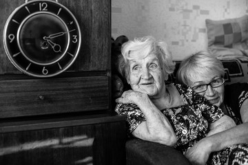 Poster - Happy elderly woman with her daughter in behind an embrace. Black and white photo.