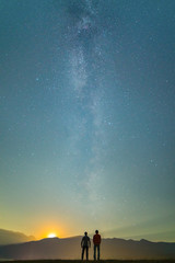 Wall Mural - The two men stand on the background of the milky way. night time