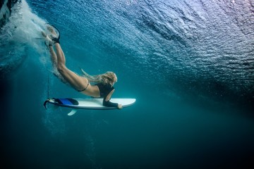 Wall Mural - blonde girl surfer holding white surf board diving duckdive under big beautiful ocean wave. turbulen