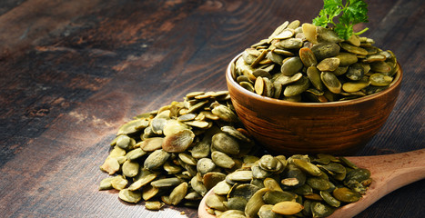 Canvas Print - Composition with bowl of pumpkin seeds on wooden table