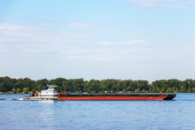Cargo Barge On The River. The Barge Is Moved By A River Tugboat