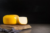 Fototapeta  - Round gouda cheese. Dark background.