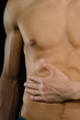 © vladorlov - Abdominal pain. A young man without a shirt. Black background.