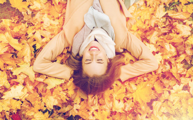 Wall Mural - beautiful happy woman lying on autumn leaves