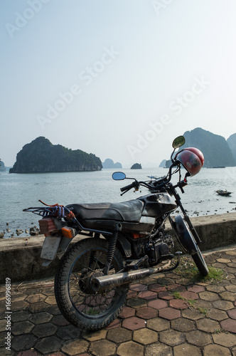 Motorcycle at Promenade and Limestone Formations and Boat in the Ocean at Ha Long Bay, Vietnam © MilesAstray