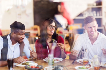 Wall Mural - happy friends eating at restaurant