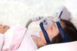 Woman wearing CPAP mask,obstructive sleep apnea therapy,bokeh background..Happy and healthy senior woman sleeping deeply on her back with CPAP machine mask and hose.