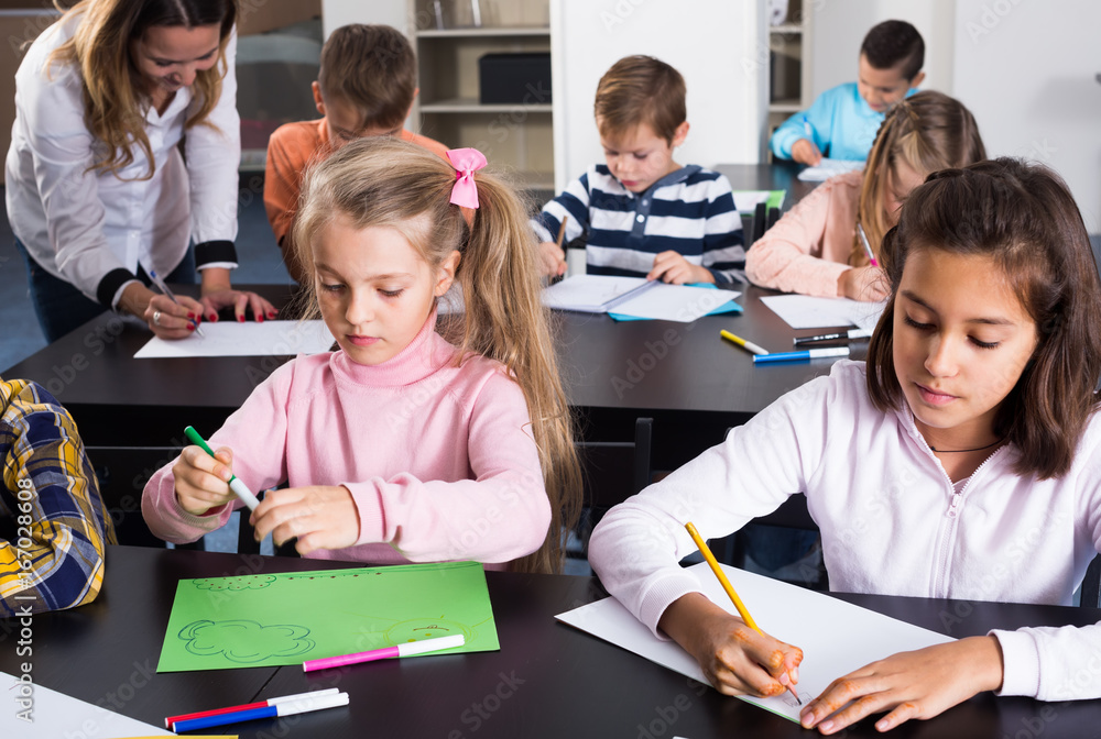 Smiling children in elementary age drawing at classroom Stock Photo ...