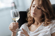 Unhappy beautiful woman looking at the glass of wine