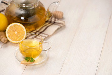 Wall Mural - Cup of ginger tea with lemon and honey on white wooden background.