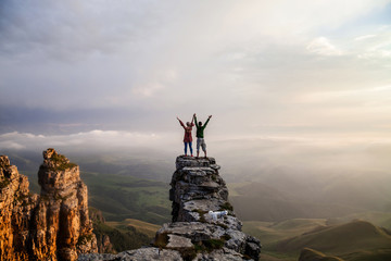 Beautiful couple standing on the cliff oi the mountain