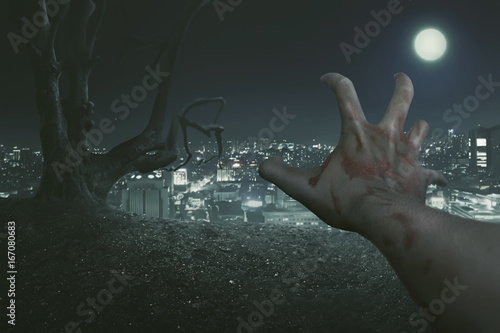 Zdjęcie XXL Koncepcja Halloween, Punkt widzenia prawej dłoni zombie, z tłem starego drzewa i miasta oświetlonego światłem księżyca w pełni.