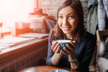 A beautiful asian woman drinking hot coffee or tea from vintage cup in modern loft cafe