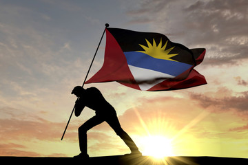 Antigua flag being pushed into the ground by a male silhouette. 3D Rendering