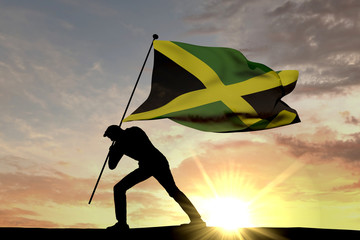Wall Mural - Jamaica flag being pushed into the ground by a male silhouette. 3D Rendering