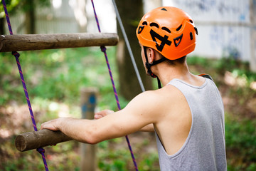 Man in an orange helmet goes up a rope ladder