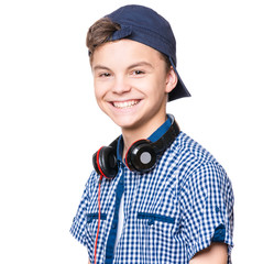 Wall Mural - Portrait of young student with cap and headphones, isolated on white background. Teen boy smiling and looking at camera. 