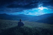 Human sitting on a hill in and enjoy moon rising