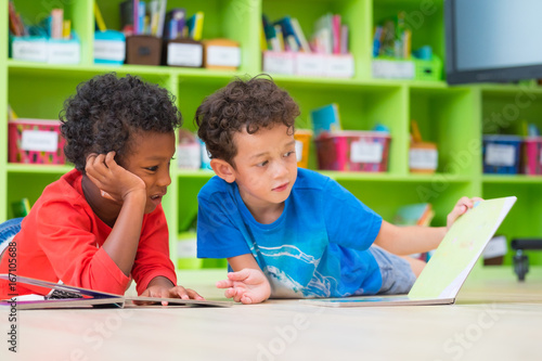 Zdjęcie XXL Dwa chłopiec dzieci kłaść na podłoga i czytelniczej bajki książce w preschool bibliotece, dzieciniec edukaci szkolnej pojęcie