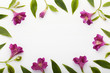 Floral frame made of magenta alstroemerias and green leaves on white background. Flat lay, top view.