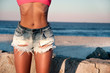 Beautiful tan woman in shorts on the beach