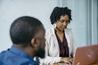© Cavan Images - Businesswoman using laptop computer while sitting with colleague in office