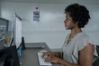 © Cavan Images - Side view of businesswoman using desktop computer while sitting at desk in office