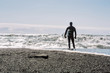 © Cavan Images - Rear view of man holding surfboard while standing near sea
