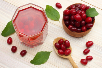 dogwood berries in wooden bowl with dogwood juice on white wooden table. top view