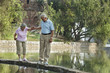 © IndiaPix - Senior man supporting woman while walking on narrow bridge at park