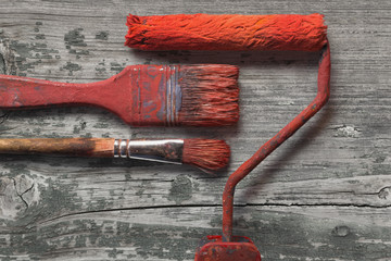 Tools for painters, set of paint brushes and roller on rustic board