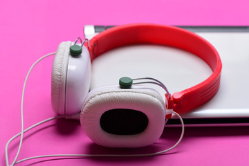 Headphones and silver laptop. Electronics isolated on magenta pink background