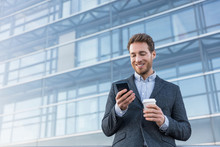 Businessman Holding Mobile Cell Phone Using App Texting Sms Message Wearing Suit. Young Urban Professional Man Using Smartphone At Office Building.