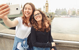 Fototapeta Londyn - Happy smiling pretty teenage girls taking selfie at Big Ben, London