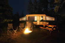 Rv Trailer, Chairs And Picnic Table Around A Glowing Campfire, Wilderness Site, Night