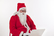 © IndiaPix - Santa Claus operating laptop over white background