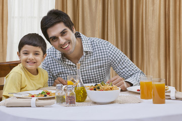 Portrait of a happy father and son having pizza at table 