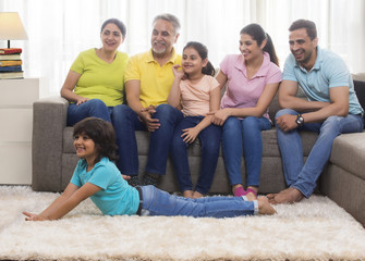 Happy family sitting together on sofa looking away