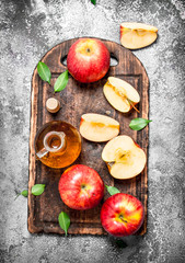 Apple cider vinegar with fresh apples on cutting Board.