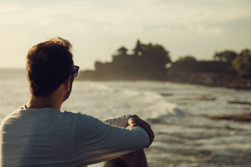 Modern man sitting on the beach and enjoying the view.