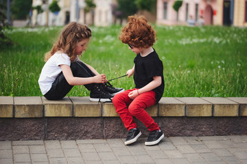 boy helps little girl tie shoelaces