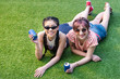 © LIGHTFIELD STUDIOS - beautiful young multiethnic women in sunglasses holding soda cans and smiling at camera while lying on grass