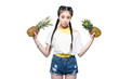 © LIGHTFIELD STUDIOS - serious young asian woman holding ripe pineapples and looking at camera isolated on white